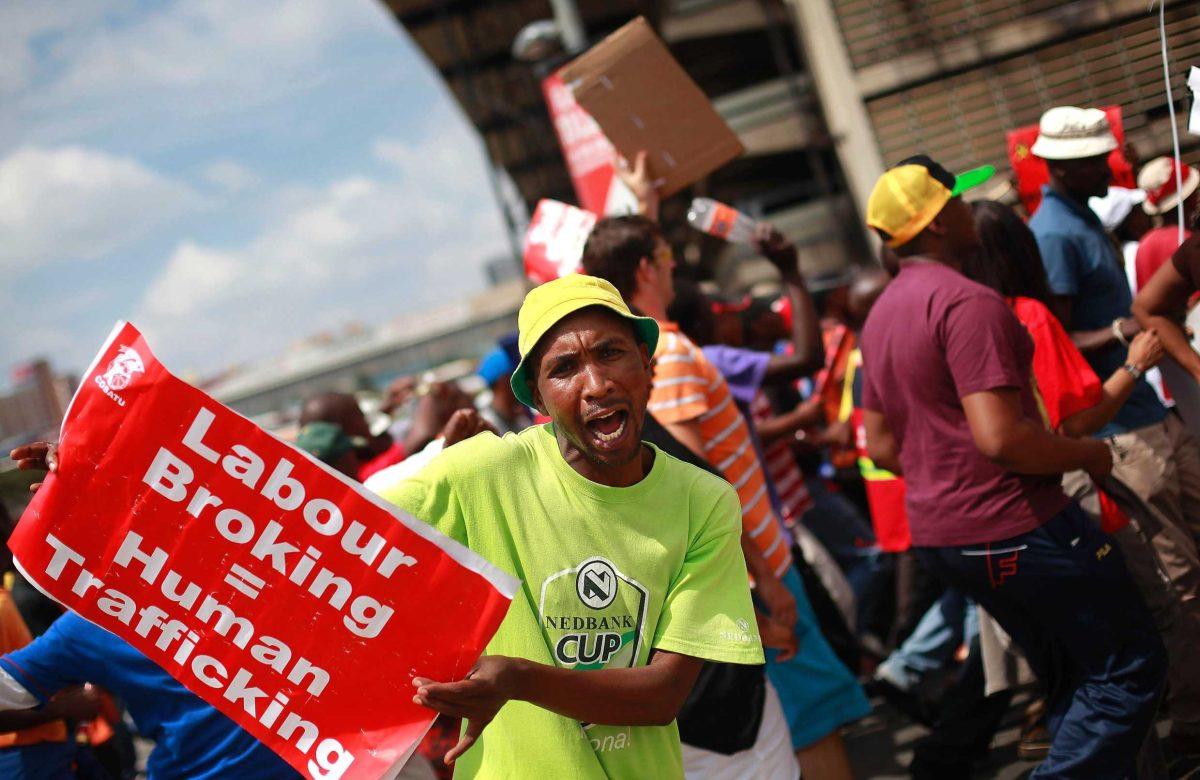 A South African protestor holding a placard Wednesday calling for the end of Labour Broking marches downtown Johannesburg, South Africa.