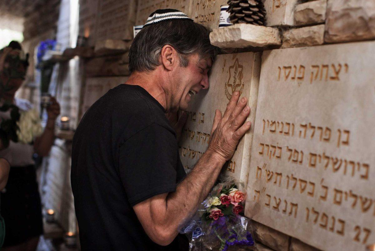 A man cries beside a memorial stone for a fallen soldier Wednesday during the annual Memorial Day ceremony at the Mt. Herzl military cemetery in Jerusalem.