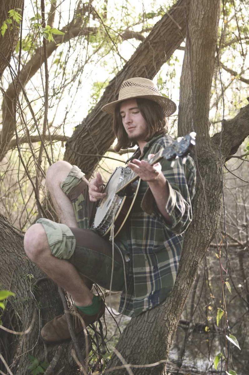 Allen Bile plays songs about southern stereotypes with his banjo in a swampy area near River Road.