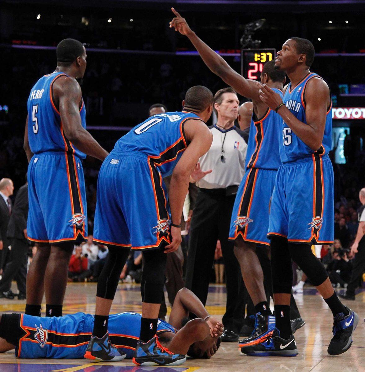 Oklahoma City Thunder players stand over teammate James Harden on Sunday after receiving a double foul from Los Angeles Lakers&#8217; Metta World Peace, who was then ejected.