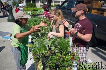 Baton Rouge residents Abbi Pounders (middle) and Kyle Fontaine (right) purchase artichoke plants Saturday at the Red Stick Farmer&#8217;s Market downtown.