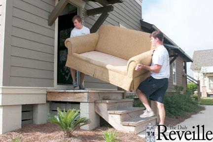 Geology junior John Anthony (right), a member of Campus Bellhops, moves a couch out of a Cottages apartment with his roommate Zach Vallee, accounting junior.