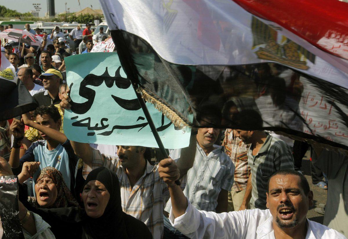 Egyptian anti-Muslim Brotherhood protesters shout slogans during a rally to denounce the country's Islamist President Mohammed Morsi and his Muslim Brotherhood group in Cairo, Egypt Friday, Aug. 24, 2012. Friday's protests were the first attempt by Morsi's opponents to stage a major demonstration against the new president. Arabic reads " Morsi is illegal." (AP Photo/Amr Nabil)