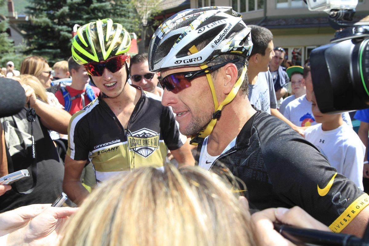 Lance Armstrong, front, jokes with reporters after his second-place finish in the Power of Four mountain bicycle race at the base of Aspen Mountain in Aspen, Colo., on Saturday, Aug. 25, 2012. Sixteen-year-old Keegan Swirbul, back, of Aspen, won the race and looks on. The race is the first public appearance for Armstrong since the U.S. Anti-Doping Association stripped him of his seven Tour de France championships and banned him for life from professional cycling. (AP Photo/David Zalubowski)