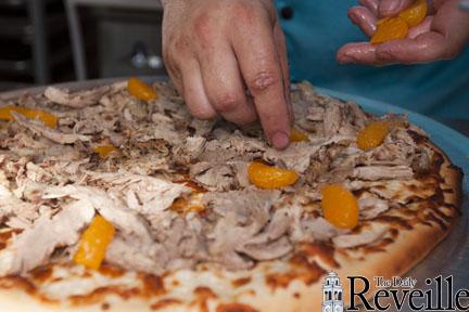 Chef Bogdan Mocanu places tangerines on a pizza August 14 with roasted duck a Jim Beam honey glaze.
 