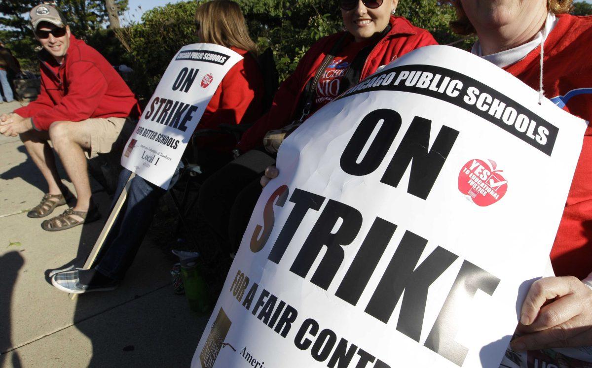 Teachers picket outside Morgan Park High School in Chicago, Tuesday, Sept. 18, 2012, as a strike by the Chicago Teachers Union continues into its second week. CTU members in the nation's third-largest city will pore over the details of a contract settlement Tuesday as the clock ticks down to an afternoon meeting in which they are expected to vote on ending a seven-day strike that has kept 350,000 students out of class. (AP Photo/M. Spencer Green)