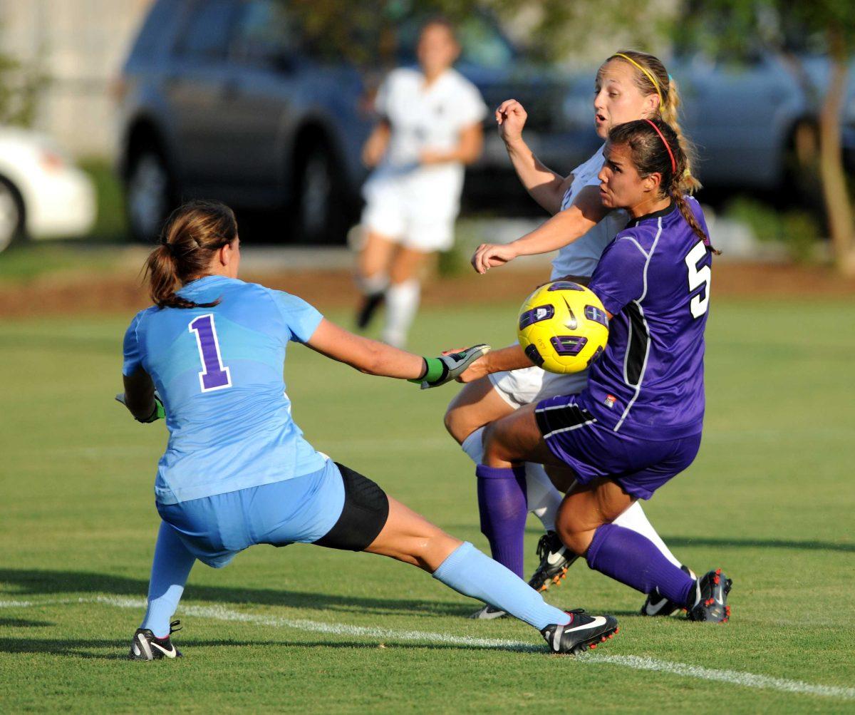 LSU senior forward Carlie Banks (27) splits the SFA freshman defender Chantal Curry (5) and junior goalkeeper Lacey Leem (1) for a goal in Tuesday's match against Stephen F. Austin State University at LSU's Soccer Complex.