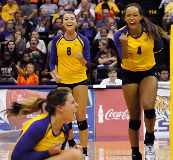 Junior middle blocker Desiree Elliot (4) celebrates after a spike with sophomore outside hitter Helen Boyle (8) and sophomore setter Malorie Pardo.
 