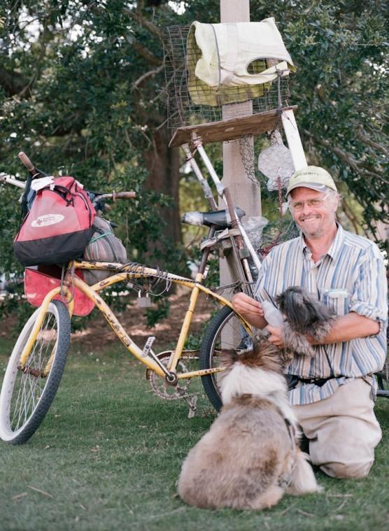 Jefferson Orwell Opals kneels near his bicycle, a homemade contraption&#160; fit to carry interesting souvenirs and his two dogs, Cayla and Ringo.
 