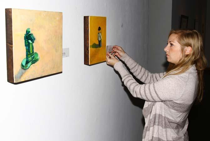 Graduate student Anna Aldridge hangs artist credentials her pieces "Ready to Come Home" (left) and "Carried Away" (right) for "The Greatest Graduate Student Art Exhibition in the History of the Universe... ...Ever, Ever!" in Foster Hall Art Gallery.
 