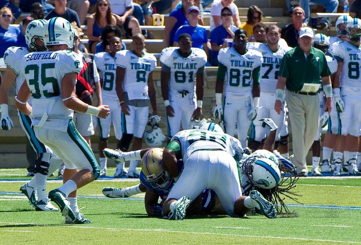 In this photo provided by the University of Tulsa, Tulane's Devon Walker, bottom right, and Julius Warmsley (92) tackle Tulsa's Kenny Welcome, bottom left, during the first half of an NCAA college football game in Tulsa, Okla., Saturday, Sept. 8, 2012. On this play, Walker was seriously hurt. (AP Photo/University of Tulsa, John Lew)