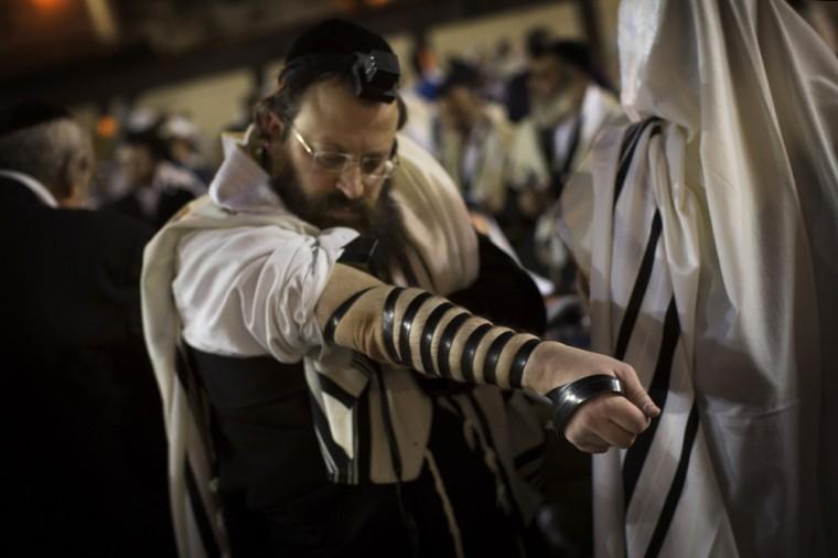 An Ultra-Orthodox Jew adjusts a Tefillin, also known as phylacteries, during a prayer at the Western Wall in Jerusalem's Old City, before the start the holiday of Rosh Hashana, early Sunday, Sept. 16, 2012. Jews will mark the holiday of Rosh Hashana, or the Jewish New Year at sundown Sunday. (AP Photo/Bernat Armangue)
 