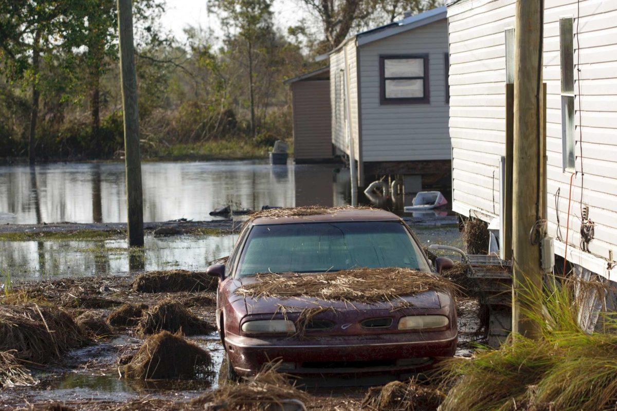 A car is covered in debris while other homes are surrounded by floodwaters in Ironton, La. after Hurricane Isaac near Louisiana Hwy 23 in Plaquemines Parish Monday, Sept. 3, 2012. (AP Photo/Matthew Hinton)