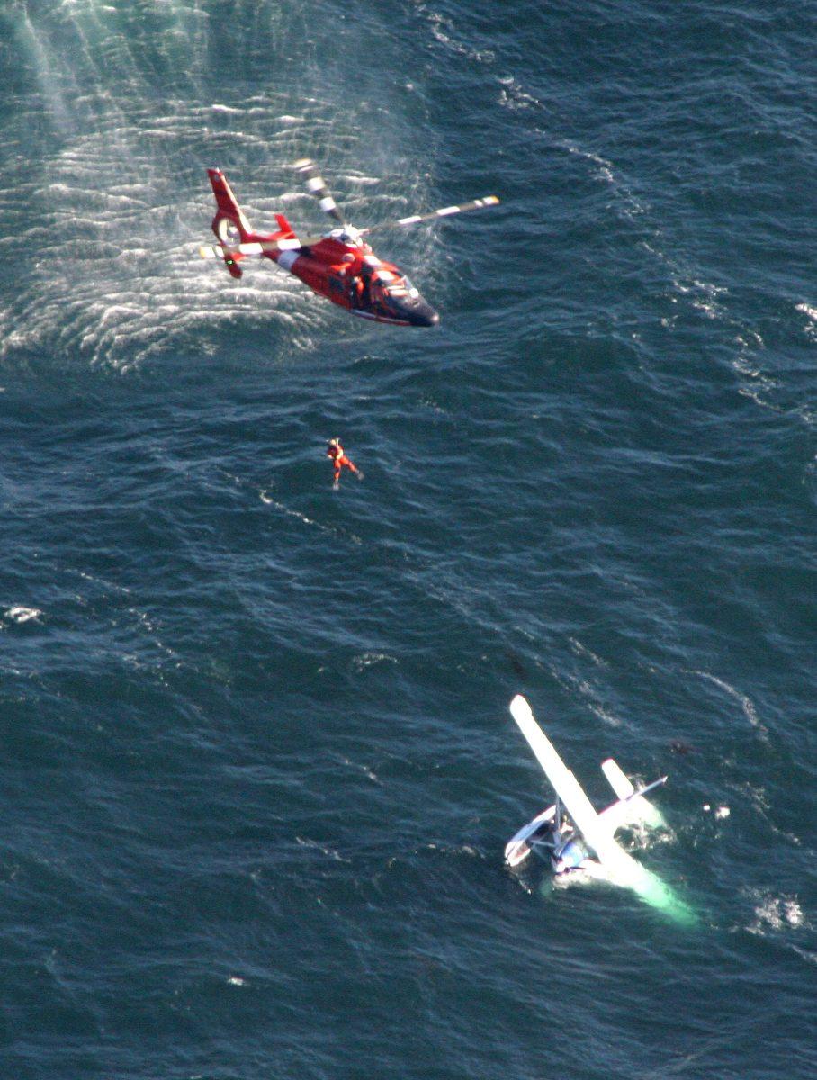 In this photo provided by the U.S. Coast Guard via the California Highway Patrol, a Coast Guard helicopter lowers a rescue swimmer to a downed aircraft in Morro Bay off California's central coast Sunday, Sept. 9, 2012. Thirty-six-year-old Stanford Shaw says he and his 77-year-old father, Stanley, were flying from Southern California to British Columbia on Sunday when the single engine of their Cessna 185 lost power. The plane sank after the two were rescued. (AP Photo/U.S. Coast Guard via the California Highway Patrol)