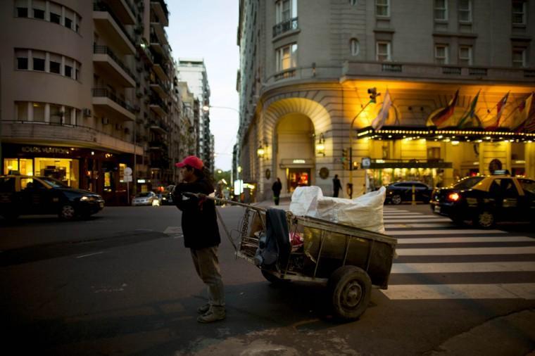 In this Sept. 26, 2012 photo, a cardboard picker stands in front of a Louis Vuitton store, left, and the Alvear Hotel, right, along Alvear Avenue in the Recoleta neighborhood in Buenos Aires, Argentina. The world's most luxurious designer brands are abandoning Argentina rather than complying with tight new government economic restrictions, leaving empty shelves and storefronts along the capital's elegant Alvear Avenue, where tourists once flocked to see the latest in fashion. (AP Photo/Natacha Pisarenko)
 