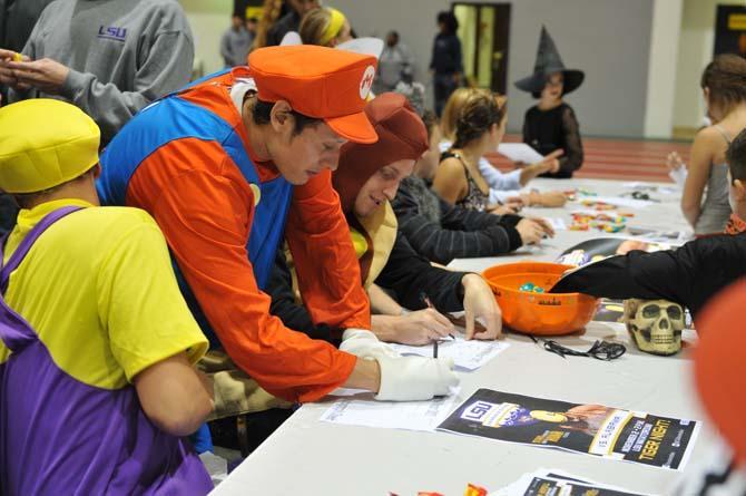 Members of the Swimming and Diving Team sign autographs Tuesday night for children at the annual Halloween BOOzar in the Carl Maddox Fieldhouse.
 