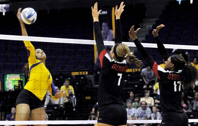 LSU junior middle blocker Desiree Elliott (4) spikes the ball past Georgia junior outside hitter Brittany Northcutt (7) and freshman middle blocker Jasmine Eatmon (17)
 