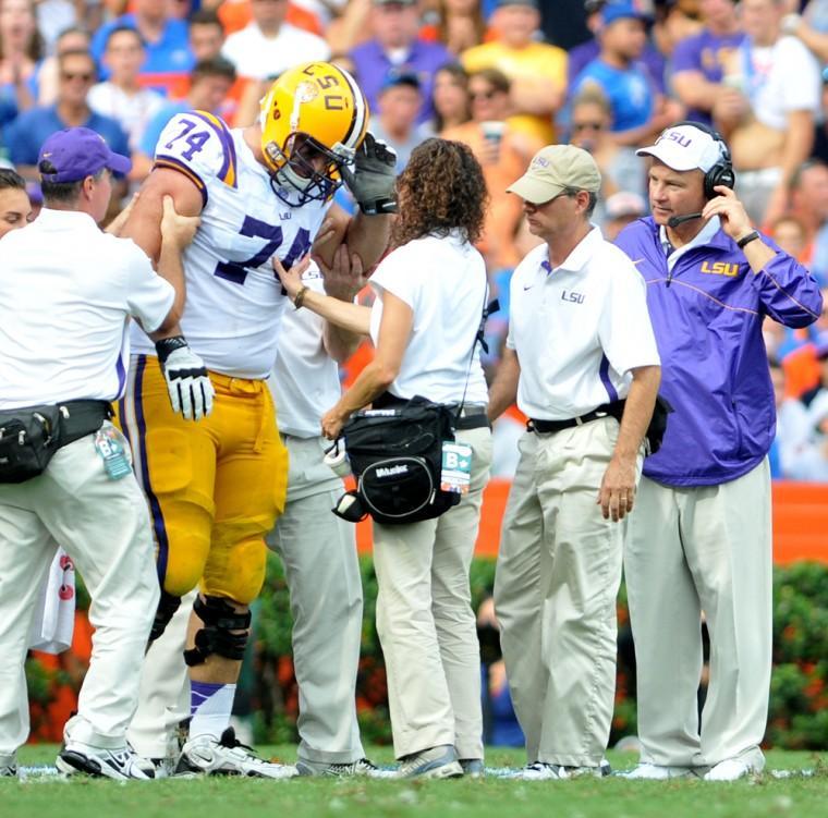 LSU football support staf help LSU junior offensive guard Josh Williford (74) off the field as head coach Les Miles watches on Saturday, Oct. 6, 2012 during the Tigers' 14-6 loss to Florida in Ben Hill Griffin Stadium in Gainesville.
 