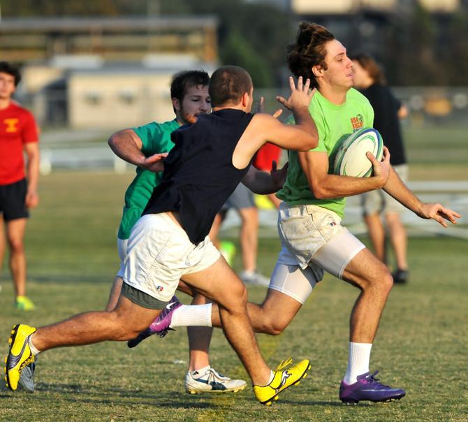 LSU freshman back Jeff Mauras tries on Tuesday, Oct. 23, 2012 to slip two defenders during rugby practice at the UREC Sport &amp; Adventure Complex.
 