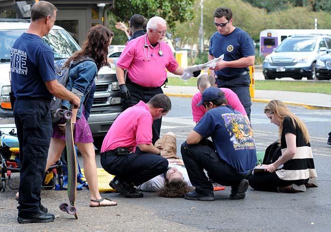 A student lies on the ground as paramedics and witnesses gather Wednesday, Oct. 17, 2012 in front of the Music and Dramatic Arts Building. The student was skateboarding across a crosswalk when a large white SUV struck him.
 