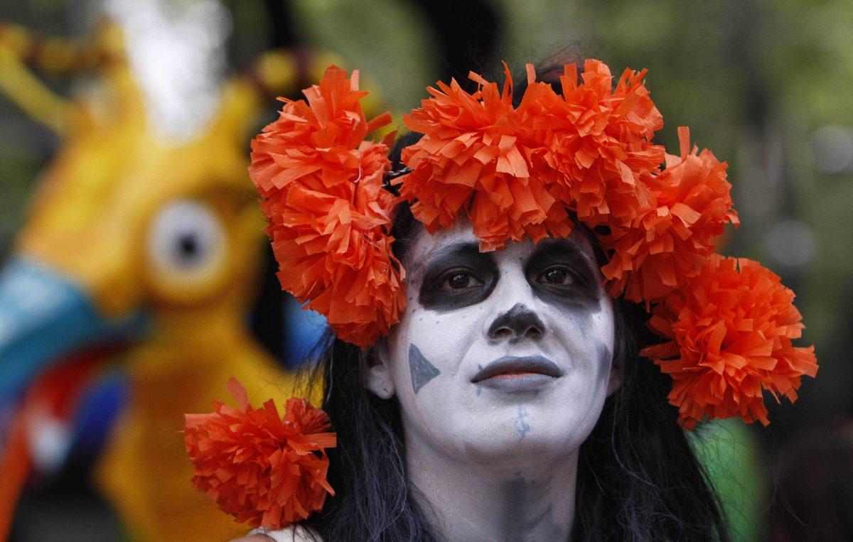 A woman dressed as a traditional Mexican "Catrina" attends a parade of large alebrijes in Mexico City, Saturday, Oct. 20, 2012 "Catrinas" are related to the tradition of Day of the Dead, celebrated on Nov. 1, and "alebrijes" are statues of fantasy animals. (AP Photo/Marco Ugarte)