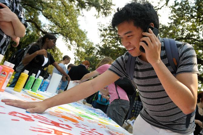 Biological sciences senior Brandon Toy leaves his fingerprints Wednesday, Oct. 10, 2012, at Spectrum's table in Free Speech Alley. Spectrum, a student organization for LGBTQ students and their allies, is celebrating National Coming Out Day.
 