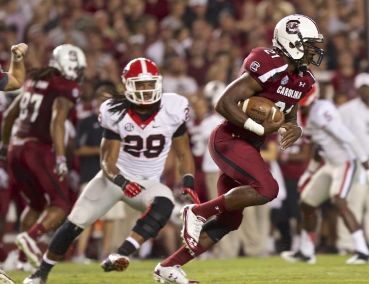 South Carolina running back Marcus Lattimore, right, breaks through the Georgia defensive line to pick up a first down as Georgia outside linebacker Jarvis Jones (29) pursues during the first quarter of an NCAA college football game in Columbia, S.C., Saturday, Oct. 6, 2012. (AP Photo/Brett Flashnick)
 