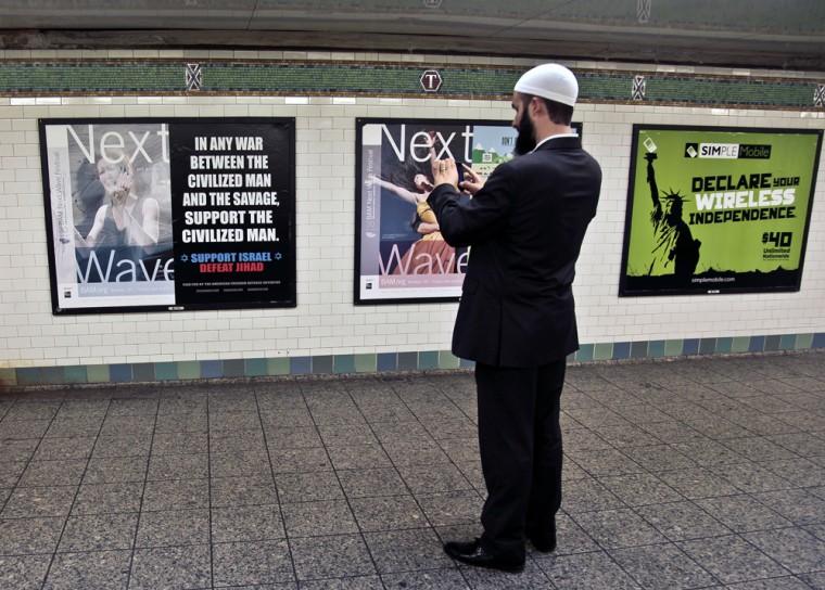 Cyrus McGoldrick, Advocacy Director for Council on American-Islamic Relations, makes a photo with his cell phone of an anti-Muslim poster on Monday, Sept. 24, 2012, in New York's Times Square subway station. A federal court forced the Metropolitan Transportation Authority to run the ad by blogger Pamela Geller, executive director of the American Freedom Defense Initiative, saying it was protected speech under the First Amendment. "As civil rights advocates, we defend Pam Geller's rights as a racist and a bigot," said McGoldrick. "Muslims are tired of being targets while extremes feed their propaganda." (AP Photo/Bebeto Matthews)
 