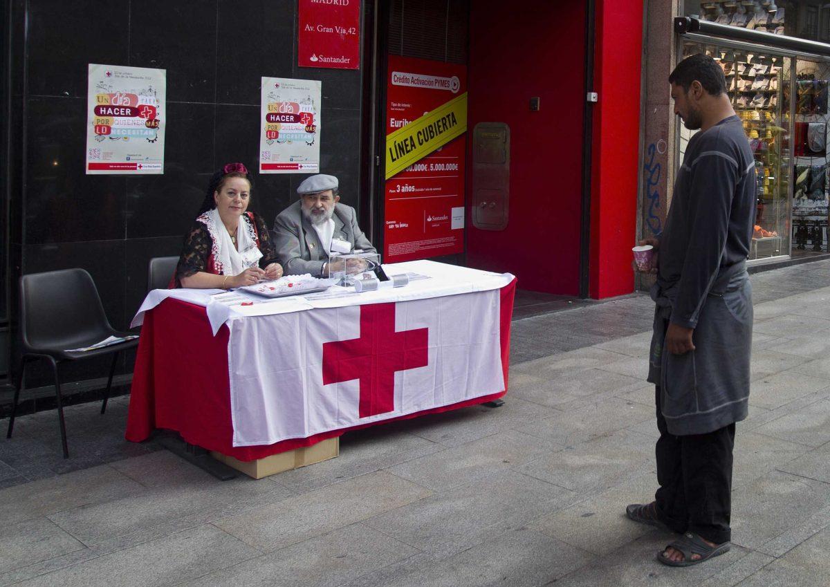 A man begging with a paper cup stands looking at Red Cross volunteers collecting money in the street, in Madrid, Wednesday Oct. 10, 2012. Spain&#8217;s Red Cross is launching its first-ever public appeal for donations to help the growing number of Spaniards in need of help because of the economic crisis.Spokesman Miguel Angel Rodriguez said Tuesday the agency is looking to round up some euro 30 million ($38.87 million) over the next two years to help an extra 300,000 people. (AP Photo/Paul White)