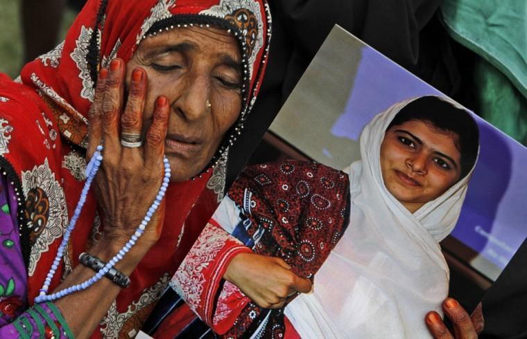 A supporter of Pakistani political party Muttahida Qaumi Movement (MQM), reacts while holding a poster of 14-year-old schoolgirl Malala Yousufzai, who was shot last Tuesday by the Taliban for speaking out in support of education for women, during a rally to condemn the attack in Karachi, Pakistan, Sunday, Oct. 14, 2012. Tens of thousands rallied in Pakistan's largest city Sunday in support of a 14-year-old girl who was shot and critically wounded by the Taliban for promoting girls' education and criticizing the militant group. (AP Photo/Shakil Adil)
 