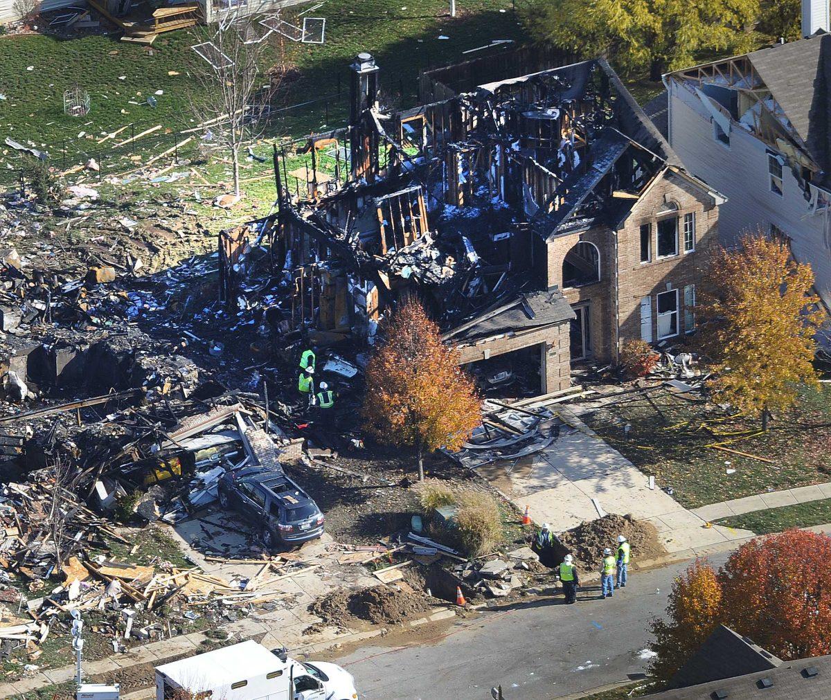 Citizens Energy workers continue their investigation Monday afternoon Nov. 12, 2012 by digging into the front sidewalk looking for possible explanation into the explosion of a house in Indianapolis. The search for what caused a massive, deadly explosion that rocked an Indianapolis neighborhood turned to natural gas Monday, with officials checking gas lines and a homeowner saying a problem furnace could be to blame. (AP Photo/WTHR Chopper 13/The Indianapolis Star, Matt Kryger) NO SALES