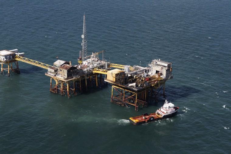 In this aerial photograph, a supply vessel moves near an oil rig damaged by an explosion and fire, Friday, Nov. 16, 2012, in the Gulf of Mexico about 25 miles southeast of Grand Isle, La. Four people were transported to a hospital with critical burns and two were missing. (AP Photo/Gerald Herbert)
 