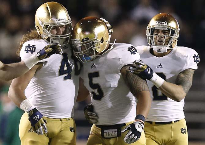 Notre Dame linebacker Manti Te'o is congratulated by teammates Dan Fox and Bennett Jackson, right, after his interception during the second half of Notre Dame's 21-6 win over Boston College in a NCAA college football game in Boston Saturday, Nov. 10, 2012. (AP Photo/Winslow Townson)
 