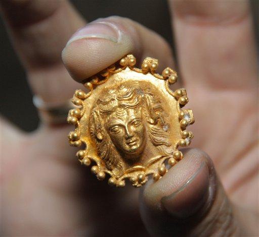 Archaeologist shows an artifact, part of 2,400-year old golden hoard found in an ancient Thracian tomb in northern Bulgarian village of Sveshtari, some 400 kilometer (250 miles) northeast of Sofia, on Thursday, Nov 8, 2012. Prof. Diana Gergova , archeologist and team leader said that among the artifacts, dated back to the end of the fourth or the beginning of the third century B.C., were gold jewelry and applications for horse trappings, a tiara with reliefs of lions and fantasy animals, as well as four bracelets and a ring. (AP Photo/ImpactPressGroup)
 