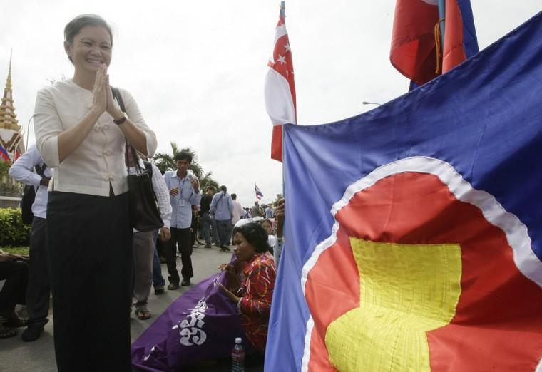 A Cambodian opposition Sam Rainsy's party member Mu Sochua, left, greets protesters as she walks near ASEAN's flag at the outside the National Assembly, in Phnom Penh, Cambodia, Friday, Nov. 16, 2012. Nearly one thousand of protesters gathered on Friday to demand human rights and democracy in ASEAN bloc. Southeast Asian leaders plan to adopt a human rights declaration aimed at fighting torture and illegal arrests in a region notorious for violations, despite criticism that the pact falls short of international standards. (AP Photo/Heng Sinith)
 