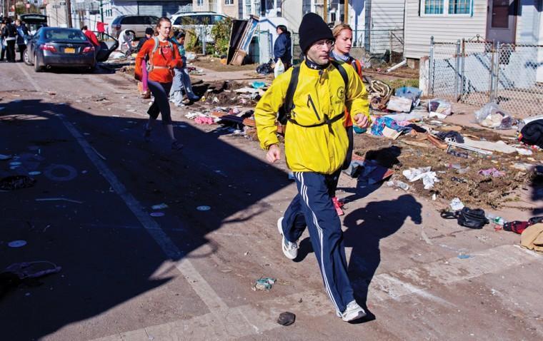 Carrying a backpack with goods and supplies, marathon runner Eitan Tabak runs past debris in the hard hit Midland Beach neighborhood of the Staten Island borough of New York, Sunday, Nov. 4, 2012. Background right is marathon runner Michelle Mascioli and far left marathon runner Rachel Wheeler of New York. With the cancellation of the New York Marathon, hundreds of runners, wearing their marathon shirts and backpacks full of supplies, took the ferry to hard-hit Staten Island and ran to neighborhoods hard hit by Superstorm Sandy to help. (AP Photo/Craig Ruttle)
 