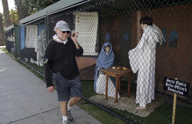 FILE - In this Dec. 13, 2011 file photo, a man walks past two of the traditional Nativity scenes along Ocean Avenue at Palisades Park in Santa Monica, Calif. Avowed atheist Damon Vix last year won two-thirds of the booths in the annual, city-sponsored lottery to divvy up spaces in the live-sized Nativity display. But he only put up one thing: A sign that read "Religions are all alike - founded on fables and mythologies." Vix left the rest of his allotted spaces empty, and in so doing, upended a Christmas tradition that began in Santa Monica nearly 60 years ago. (AP Photo/Ringo H.W. Chiu, file)
 