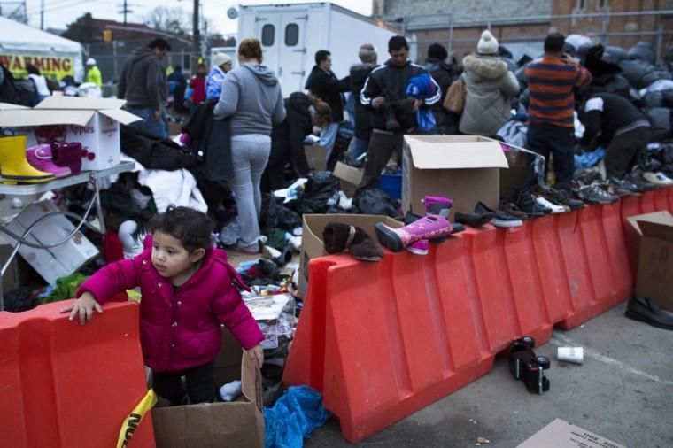 A young girl plays as residents search through donated clothing piles in the Rockaways, Saturday, Nov. 10, 2012, in the Queens borough of New York. Despite power returning to many neighborhoods in the metropolitan area after Superstorm Sandy crashed into the Eastern Seaboard, many residents of the Rockaways continue to live without power and heat due to damage caused by Sandy. (AP Photo/John Minchillo)
 