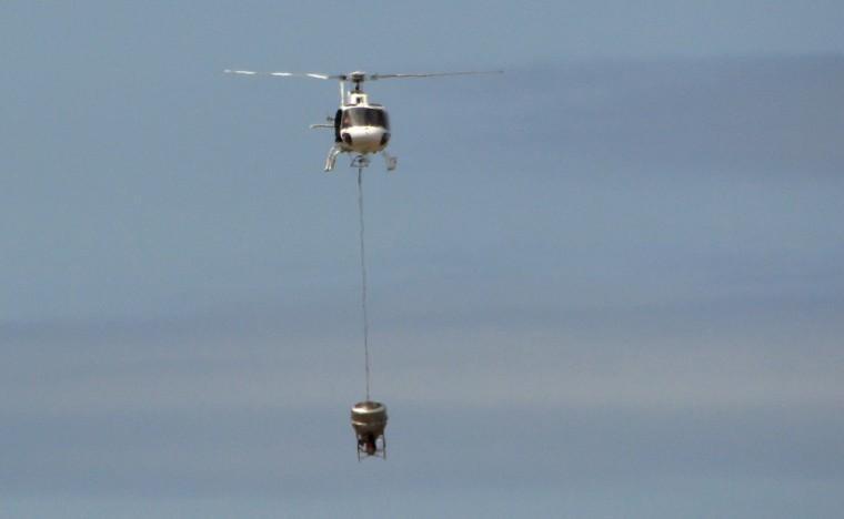 In this Nov. 11, 2012 photo released by Galapagos National Park, a helicopter tests carrying a container that will hold poisonous bait to kill rats on the Galapagos Islands, over Baltra Island. To preserve the unique birds, reptiles and native plants that make the Galapagos Islands such an ecological treasure, authorities will start on Wednesday, Nov. 14, 2012 phase II of a mass kill-off of black and Norway rats, an invasive species introduced to the Pacific Ocean islands by whalers and buccaneers beginning in the 17 century. (AP Photo/Galapagos National Park)
 