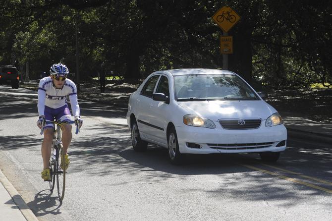 LSU Cycling Club member Joey Bacala shares the street with a passing vehicle during Tuesday afternoon on Highland Road.
 