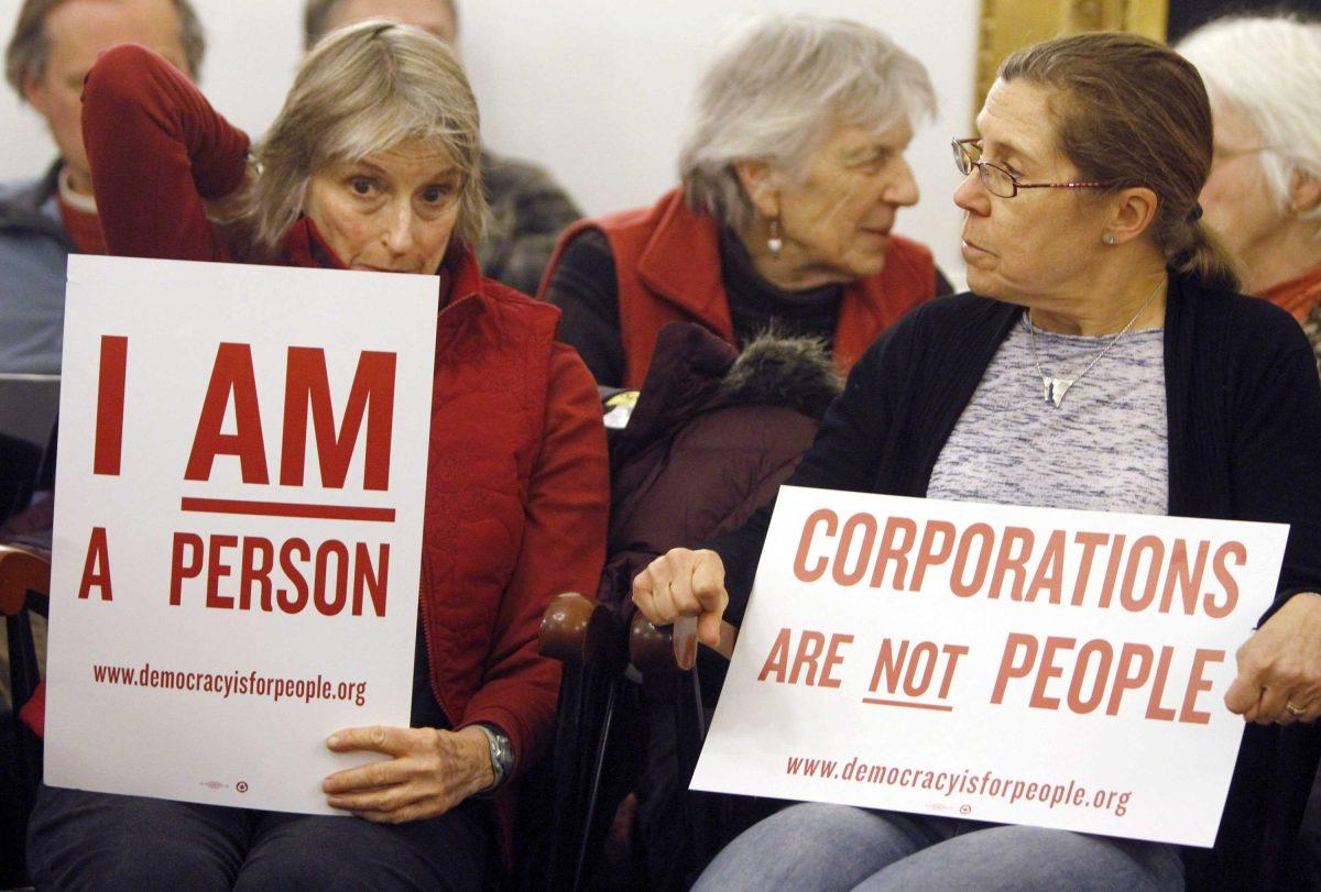 In this Jan. 20, 2012 photo, people hold signs during a gathering on the anniversary of the Citizens United decision in Montpelier, Vt. First, it was the Vermont senator with socialist leanings. Then it was Jerry of Ben &amp; Jerry's ice cream fame. Now there are about 50 Vermont communities ready to chime in on a proposal to pass a Constitutional amendment to clarify that corporations do not have the same rights as human beings., (AP Photo/Toby Talbot)