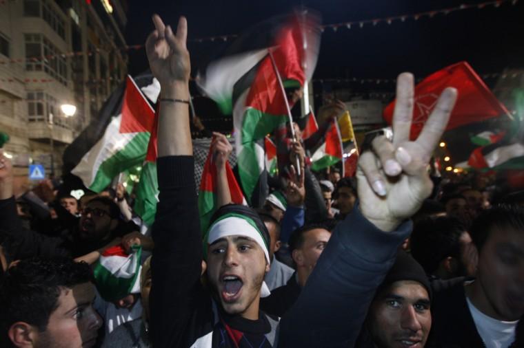 Palestinians celebrate as they watch a screen showing the U.N. General Assembly votes on a resolution to upgrade the status of the Palestinian Authority to a nonmember observer state, In the west bank city of Ramallah, Thursday, Nov. 29, 2012. The U.N. General Assembly has voted by a more than two-thirds majority to recognize the state of Palestine. The resolution upgrading the Palestinians' status to a nonmember observer state at the United Nations was approved by the 193-member world body late Thursday by a vote of 138-9 with 41 abstentions. (AP Photo/Majdi Mohammed)
 