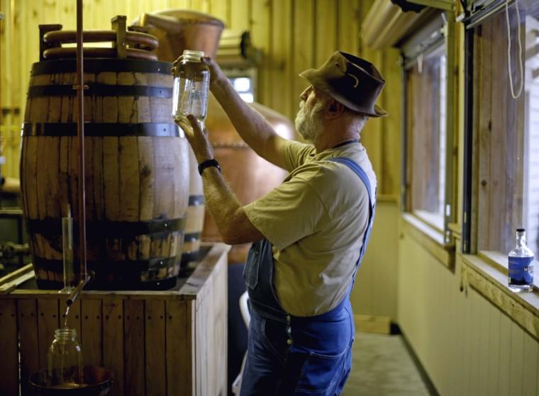 in this Friday, Nov. 16, 2012 photo, distiller Bob Suchke checks the clarity of a batch of genuine corn whisky before its tempered in the Dawsonville Moonshine Distillery, in Dawsonville, Ga. Distillers are making their first batches of legal liquor in this tiny Georgia town's hall, not far from the mountains and the maroon, orange and gold canopy of trees that once hid bootleggers from the law. (AP Photo/David Goldman)
 