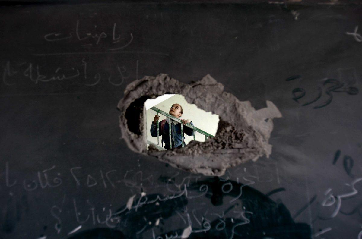 A Palestinian schoolgirl is seen through a hole in a blackboard days after an Israeli strike hit a school in Gaza City, Monday, Nov. 26, 2012. Israel launched its offensive on Nov. 14 in a bid to halt months of Palestinian rocket attacks. It says it inflicted heavy damage on Gaza militants, but the territory's armed groups fired hundreds of rockets into Israel before a cease-fire was declared Wednesday, Nov. 21, 2012.(AP Photo/Adel Hana)