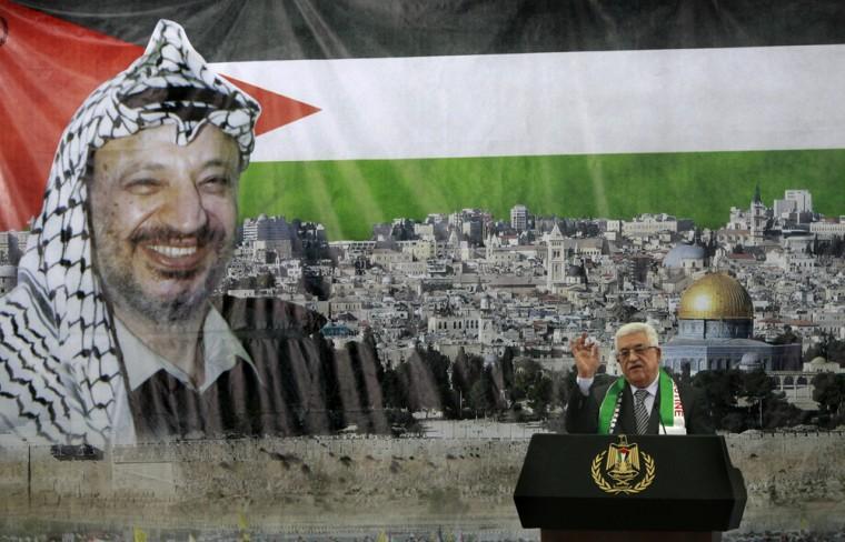 Palestinian President Mahmoud Abbas speaks during ceremony marking the 8th anniversary of Yasser Arafat's death, in the West Bank city of Ramallah, Sunday, Nov. 11, 2012. Banner behind depicts Arafat, the Dome of the Rock and a Palestinian flag.(AP Photo/Majdi Mohammed)
 