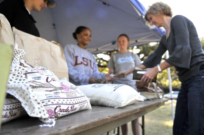 Jeanne Tribou (far right) purchases rice from biological engineering senior Sharis Steib (middle left) at the Biological Engineering Student Organization's annual sweet potato and rice sale on Tuesday at the corner of Highland Road and South Stadium Drive.
 