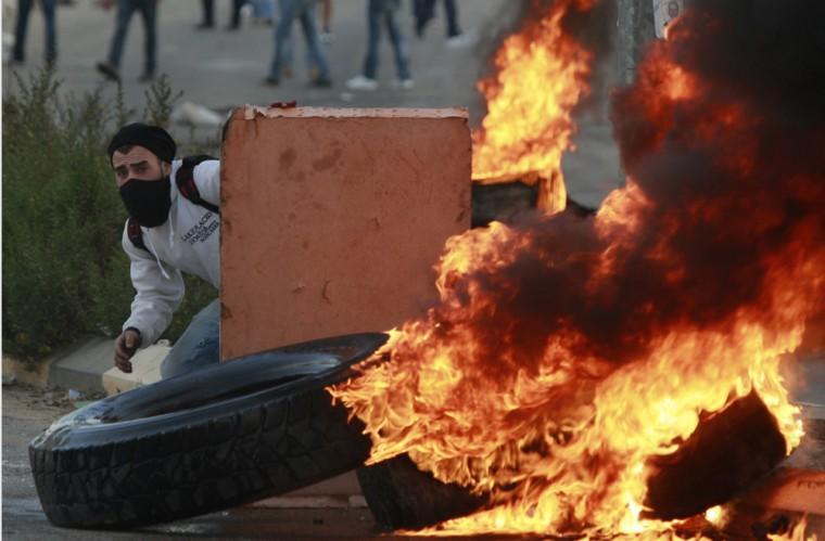 A Palestinian man hides during a protest against Israel's operations in Gaza Strip, outside Ofer, an Israeli military prison near the West Bank city of Ramallah, Sunday, Nov. 18, 2012. (AP Photo/Majdi Mohammed)
 