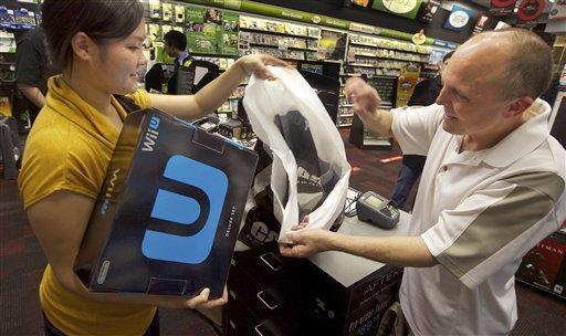 IMAGE DISTRIBUTED FOR NINTENDO - GameStop employee Lani Girran hands over a Wii U system to Kevin Owande, 51, of Renton, Wash., on a busy Black Friday at the GameStop Southcenter store in Seattle on Friday, Nov. 23, 2012. Owande was up early on Black Friday to purchase Wii U, one of the hottest products this holiday season. (Photo by Stephen Brashear/Invision for Nintendo/AP Images)
 