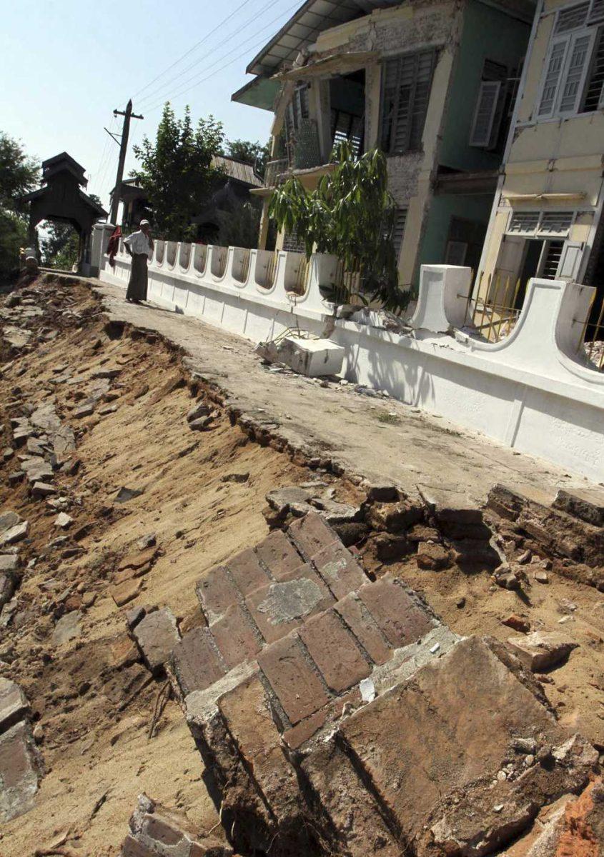 A man stands between a road and a monastery damaged by Sunday's strong earthquake at Kyaukmyaung township in Shwebo, Sagaing Division, northwest of Mandalay, Myanmar, Monday, Nov. 12, 2012. The earthquake collapsed a bridge and damaged ancient Buddhist pagodas in northern Myanmar, and piecemeal reports from the underdeveloped mining region said mines collapsed and as many as 12 people were feared dead. (AP Photo/Khin Maung Win)