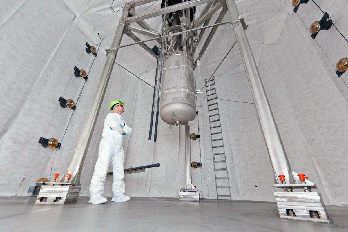 In this Oct. 16, 2012 photo provided by Sanford Lab University of California, Davis, physicist Jeremy Mock inspects the Large Underground Xenon experiment detector, cylinder at center, that has now been lowered into its 70,000-gallon home in a water tank a mile beneath the earth&#8217;s surface in a shuttered gold mine in Lead, S.D. The experiment, known as LUX, could begin collecting data on dark matter as early as February _ and, if all goes as planned, that data could answer age-old questions about the universe and its origins, scientists said Monday, Nov. 19, 2012. (AP Photo/Courtesy Sanford Lab, Matt Kapust)